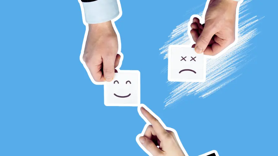Hands holding happy and unhappy customer feedback cards on a blue background, symbolizing client satisfaction.