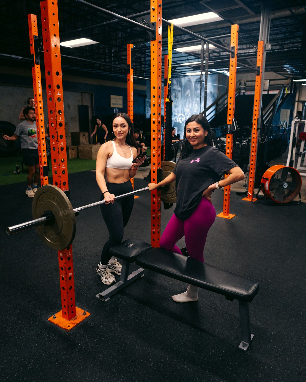 Two members smiling at the squat rack