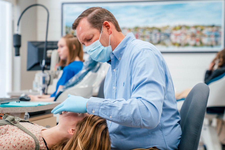Orthodontist wearing a mask and gloves examining a teen patient’s teeth during a dental check-up at Idaho Orthodontics.