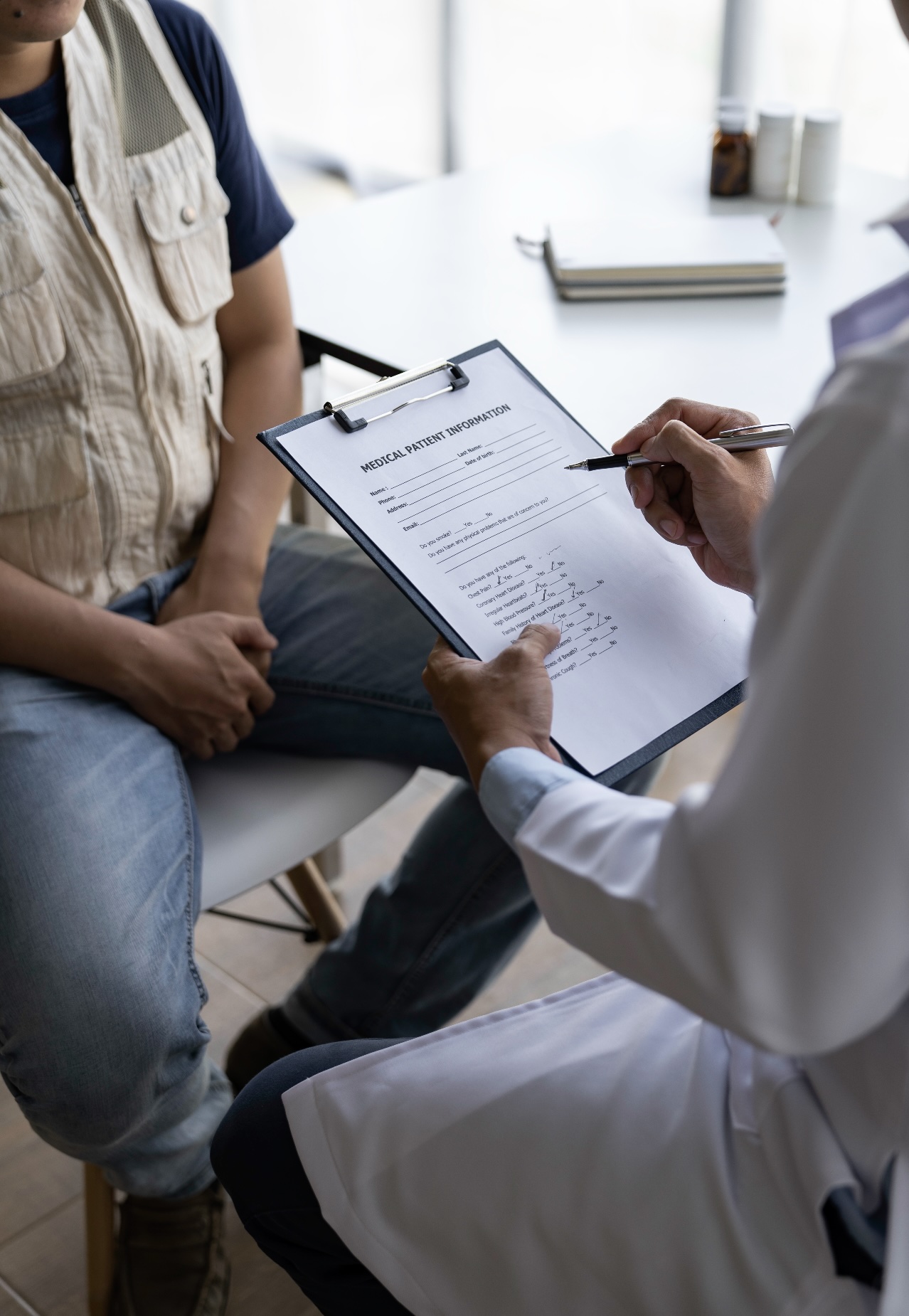Doctor reviewing medical forms with a patient during a QME or AME workers' comp evaluation in a full office