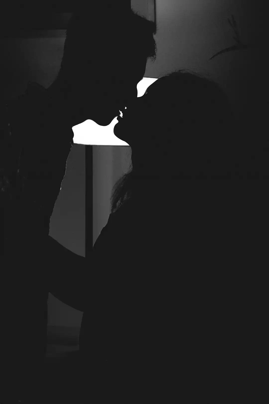 Silhouette of a couple about to kiss in a dim room