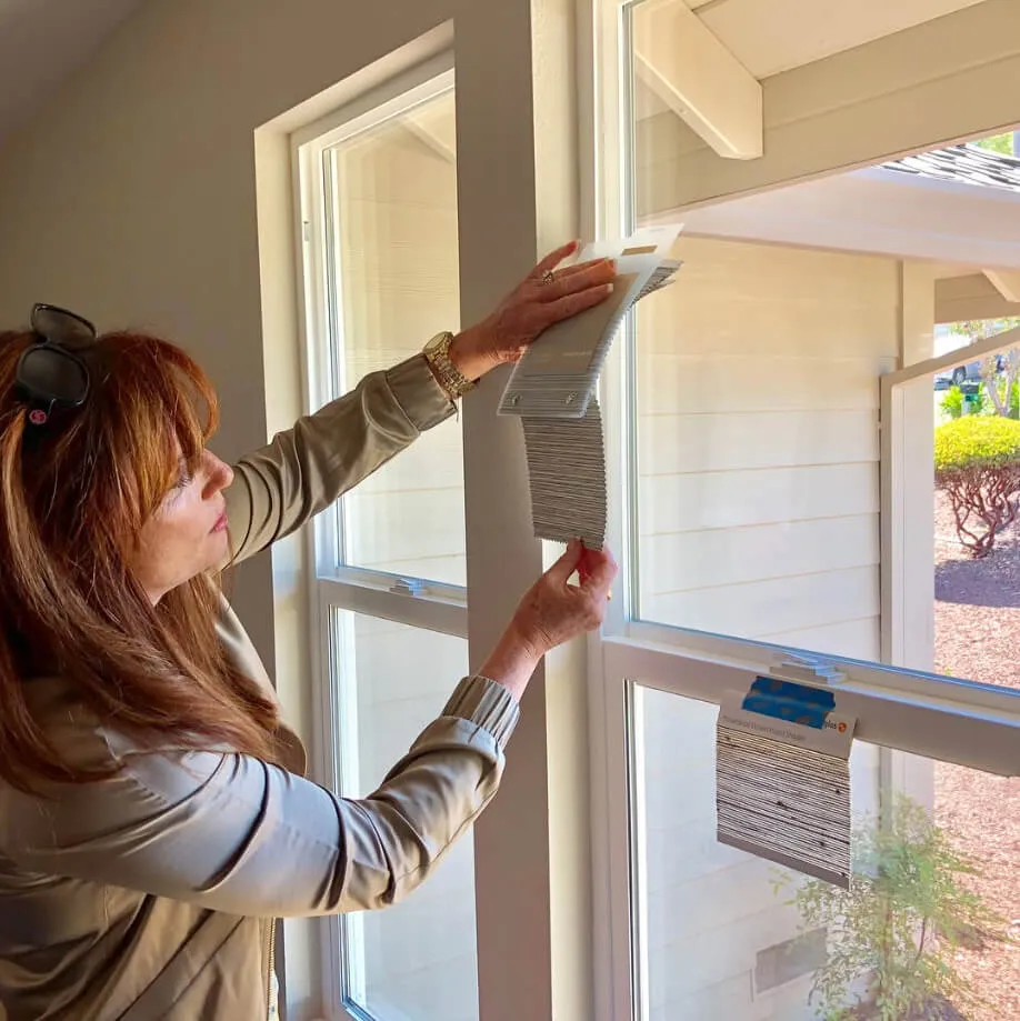 A person installing window insulation film on a large window inside a house.