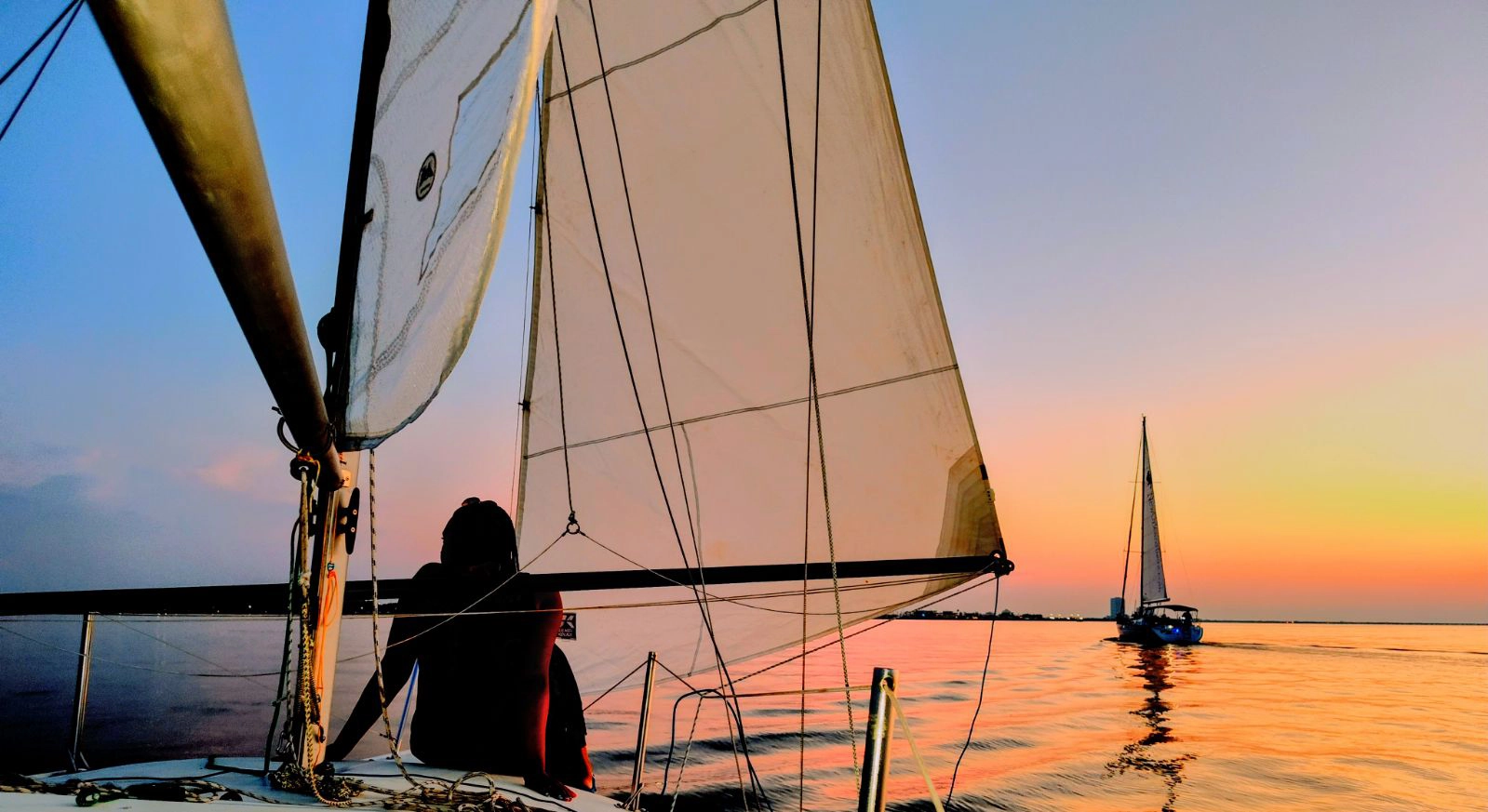 A woman on a sailboat looking out at the ocean