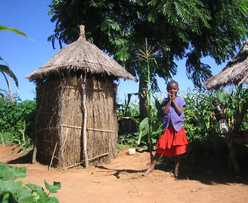 Young girl stands next to Arborloo toilet in Malawi
