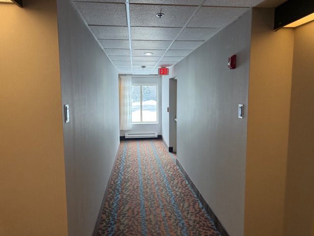 First-floor corridor at Sleep Inn before wallcovering installation, showing bare walls and old finish.
