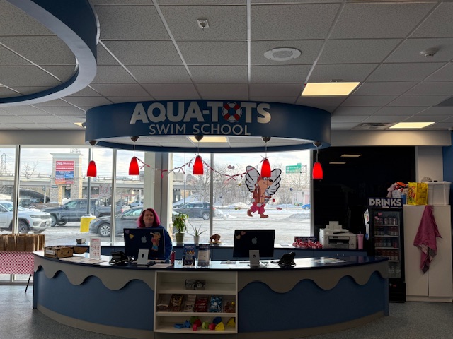 Front reception desk at Aqua-Tots Swim School with refreshed paint and lighting accents