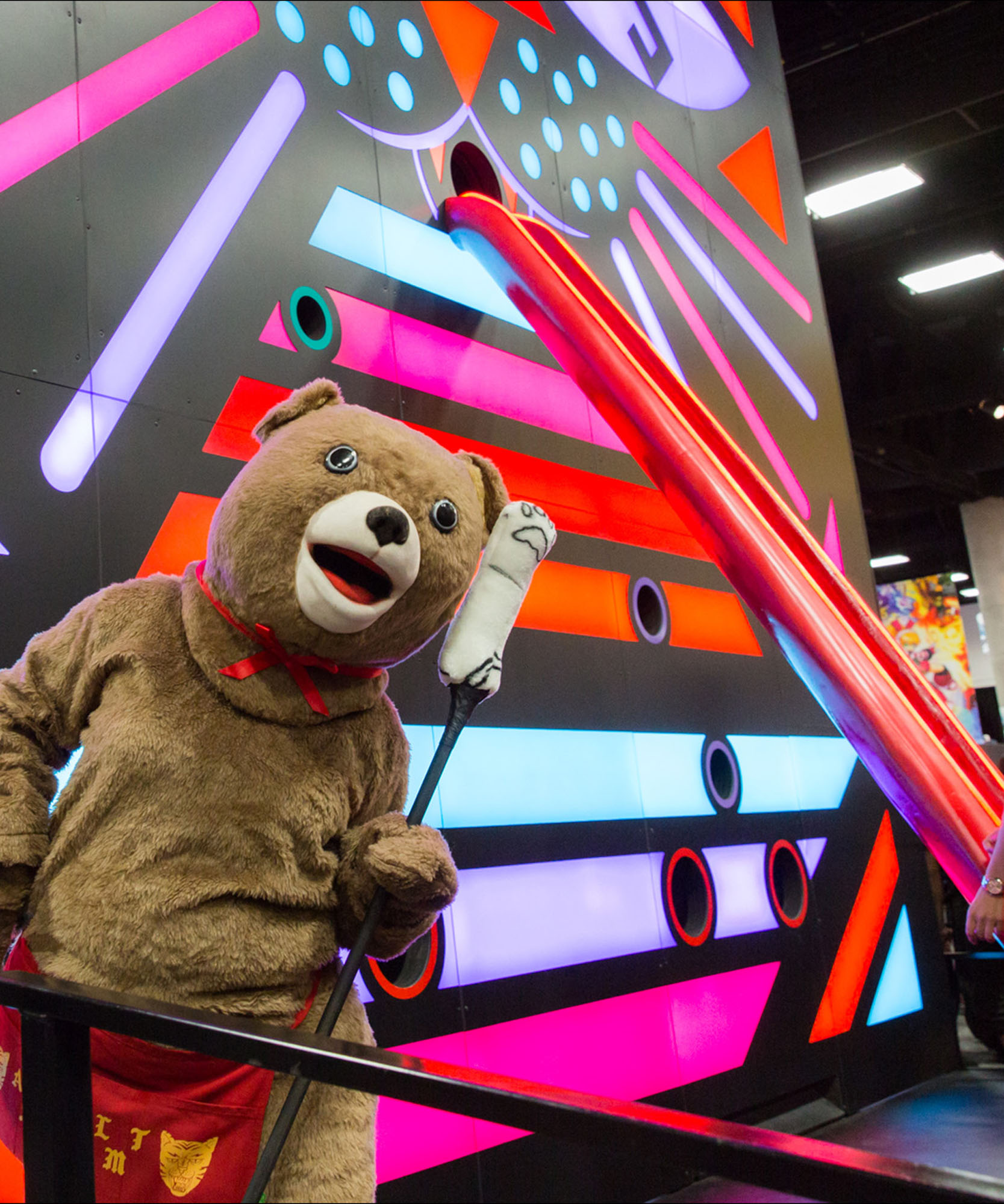 a mascot bear in front of a multi colored cat with a long tongue 