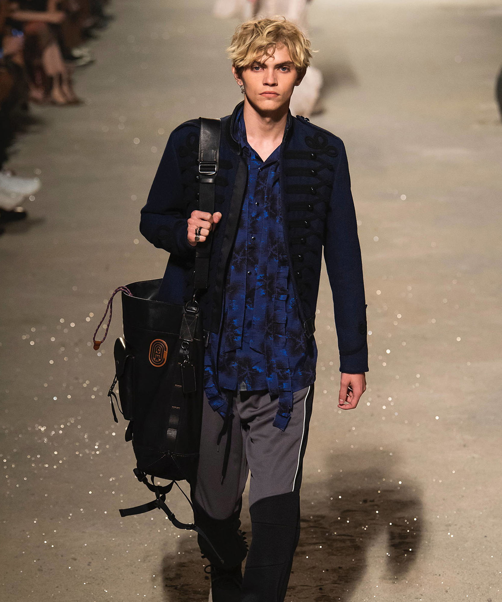 photo a male model holding back walking down a runway