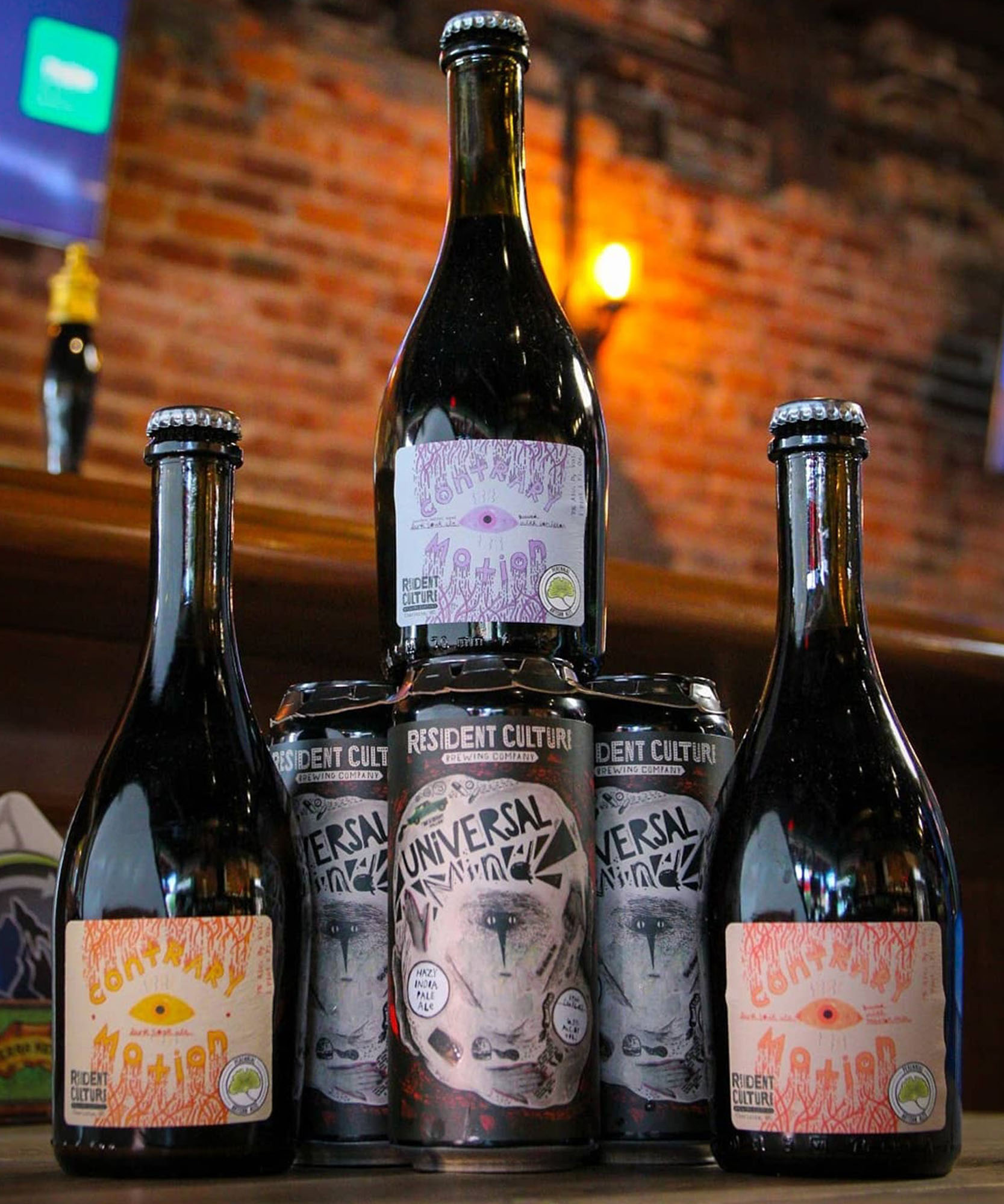 a photo of three wine bottles one on top of a canned beverage all of which have unique illustrations on them