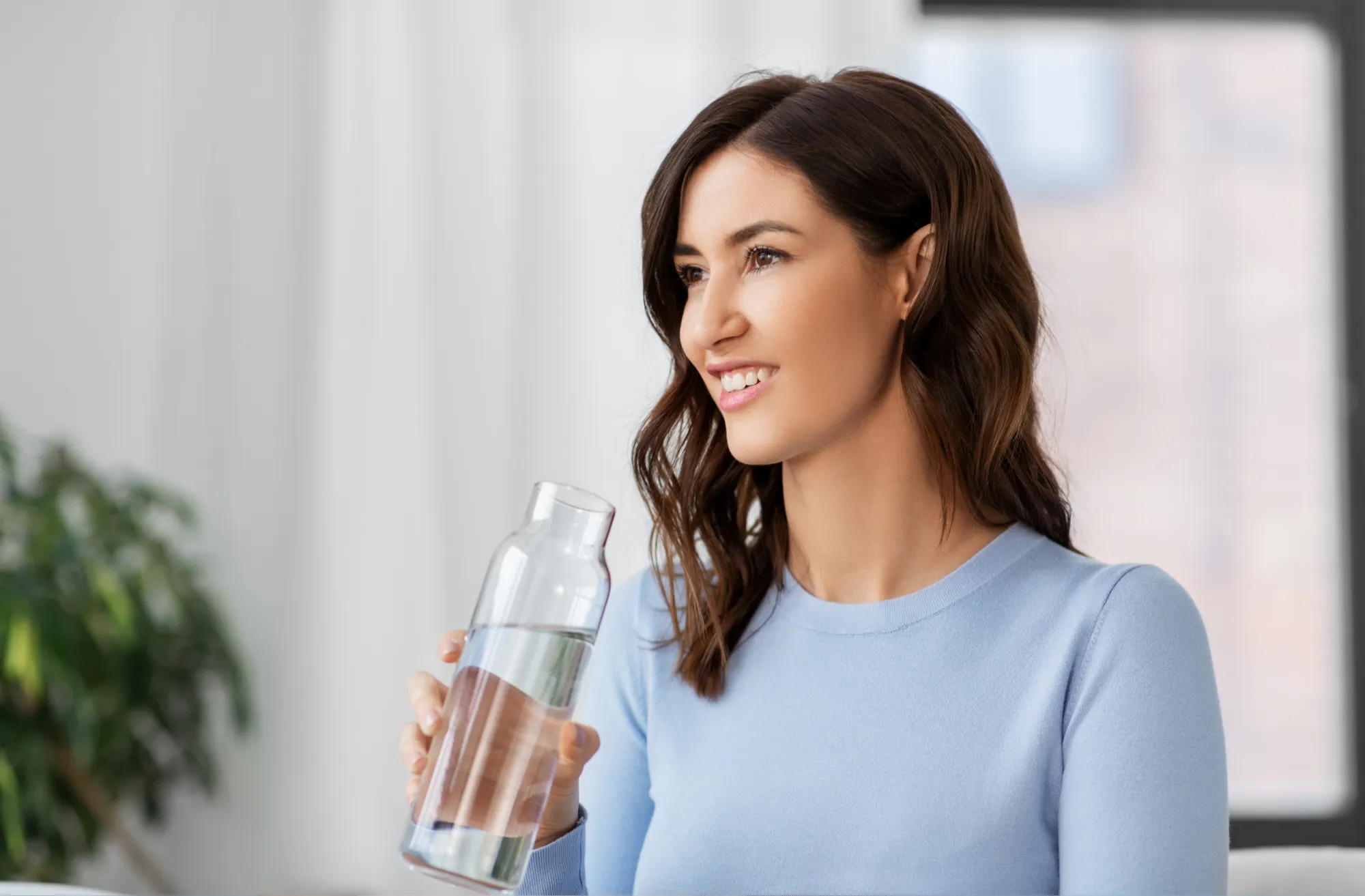 Woman drinking water to stay hydrated as part of a healthy skincare routine.