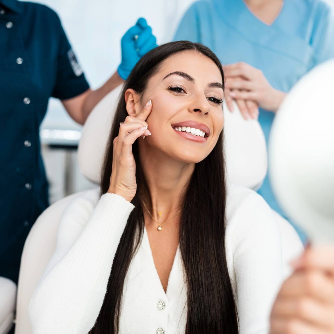 Woman smiling at mirror, medical staff in background.