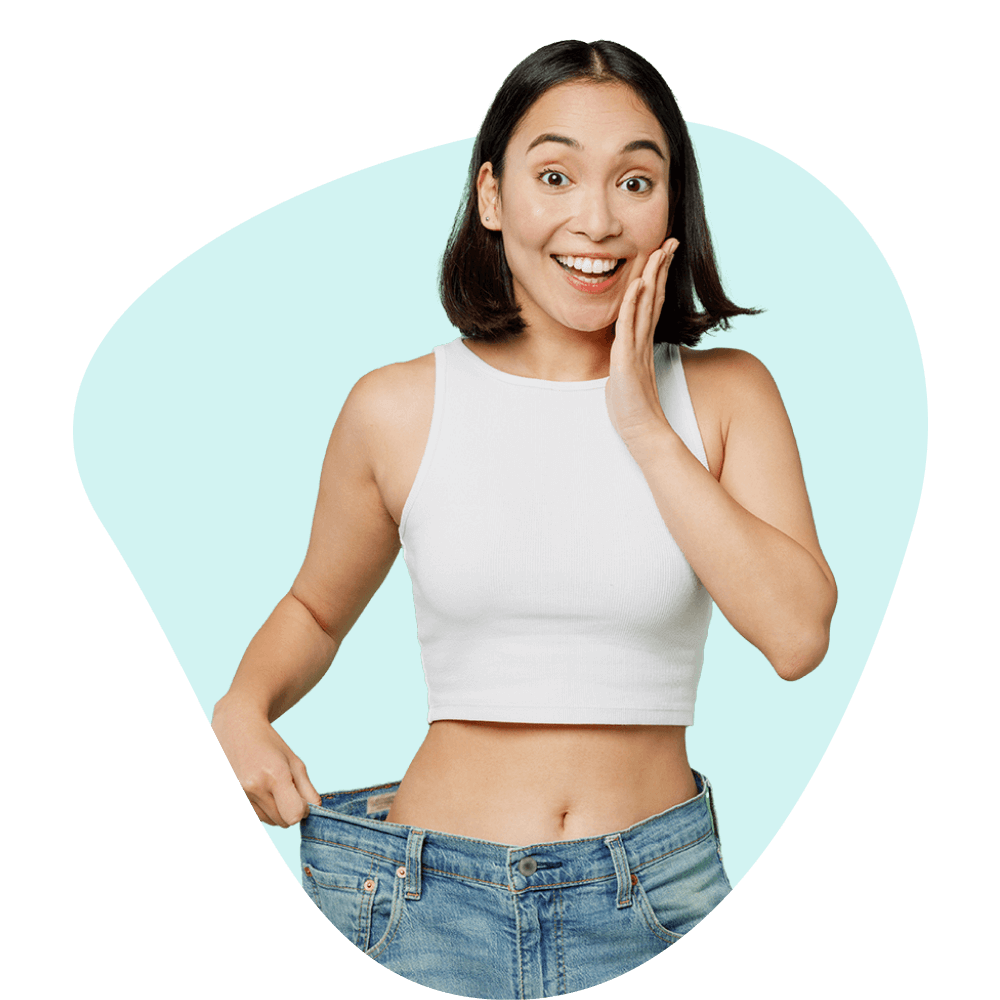 Woman in loose jeans showing weight loss progress.