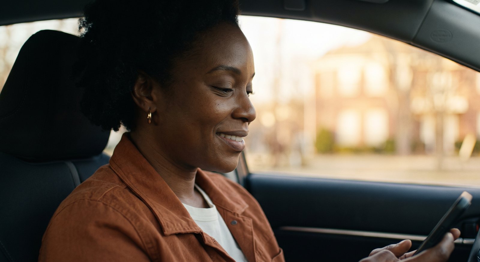 The driver smiling down at her phone while parked between rides