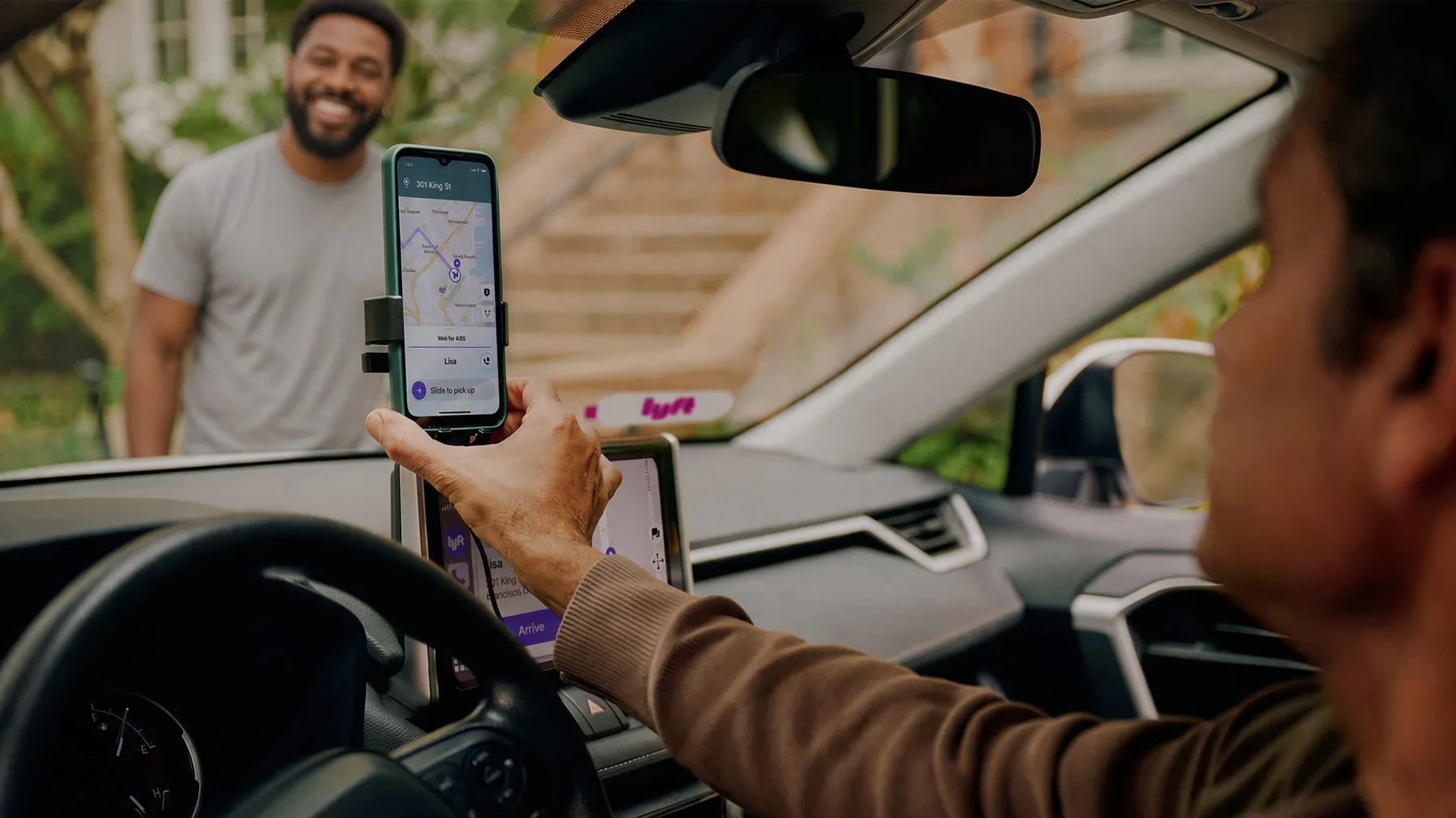 A Lyft driver tapping the phone mount to slide to pick up a rider