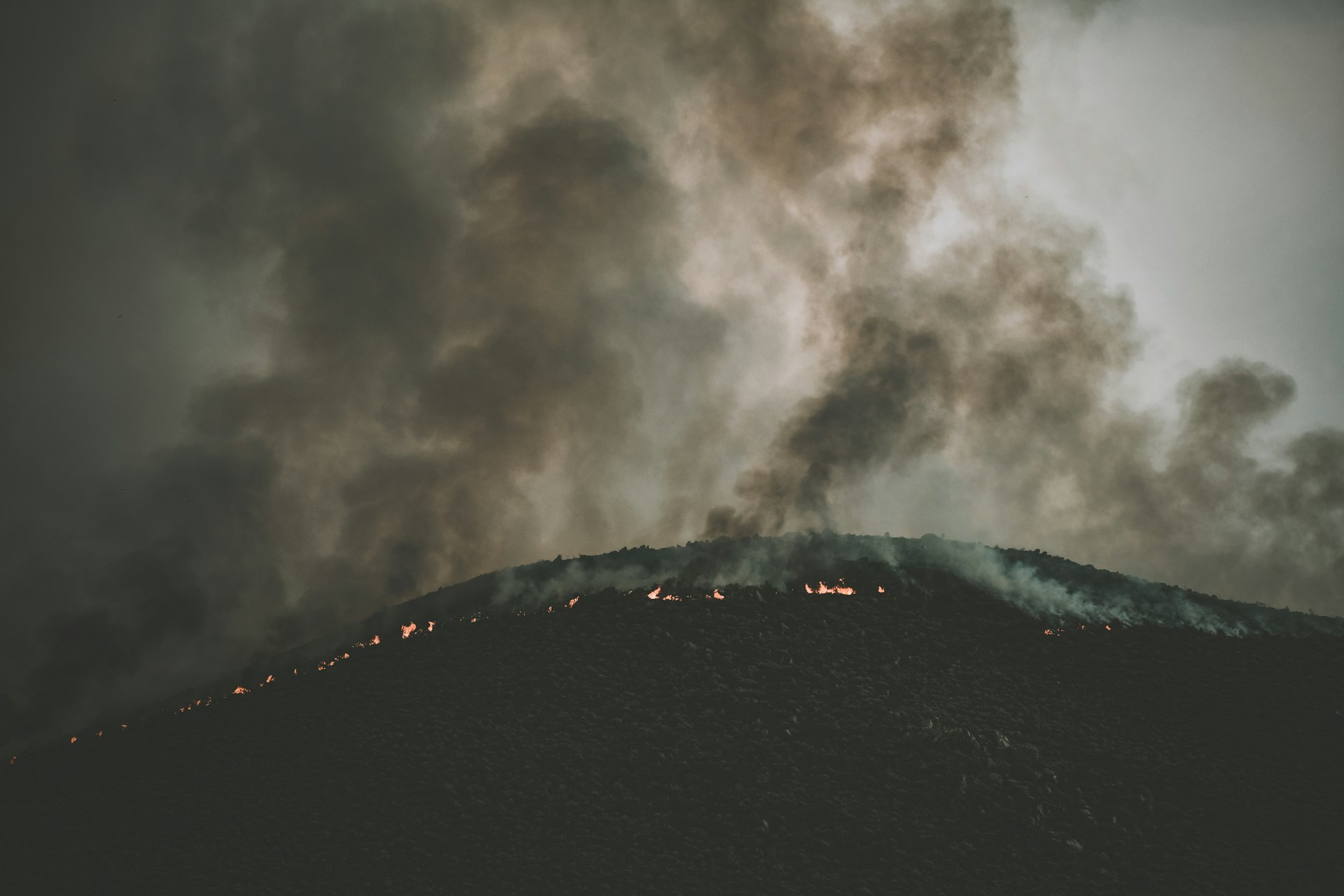 A small wildfire burning the top of a hill at night