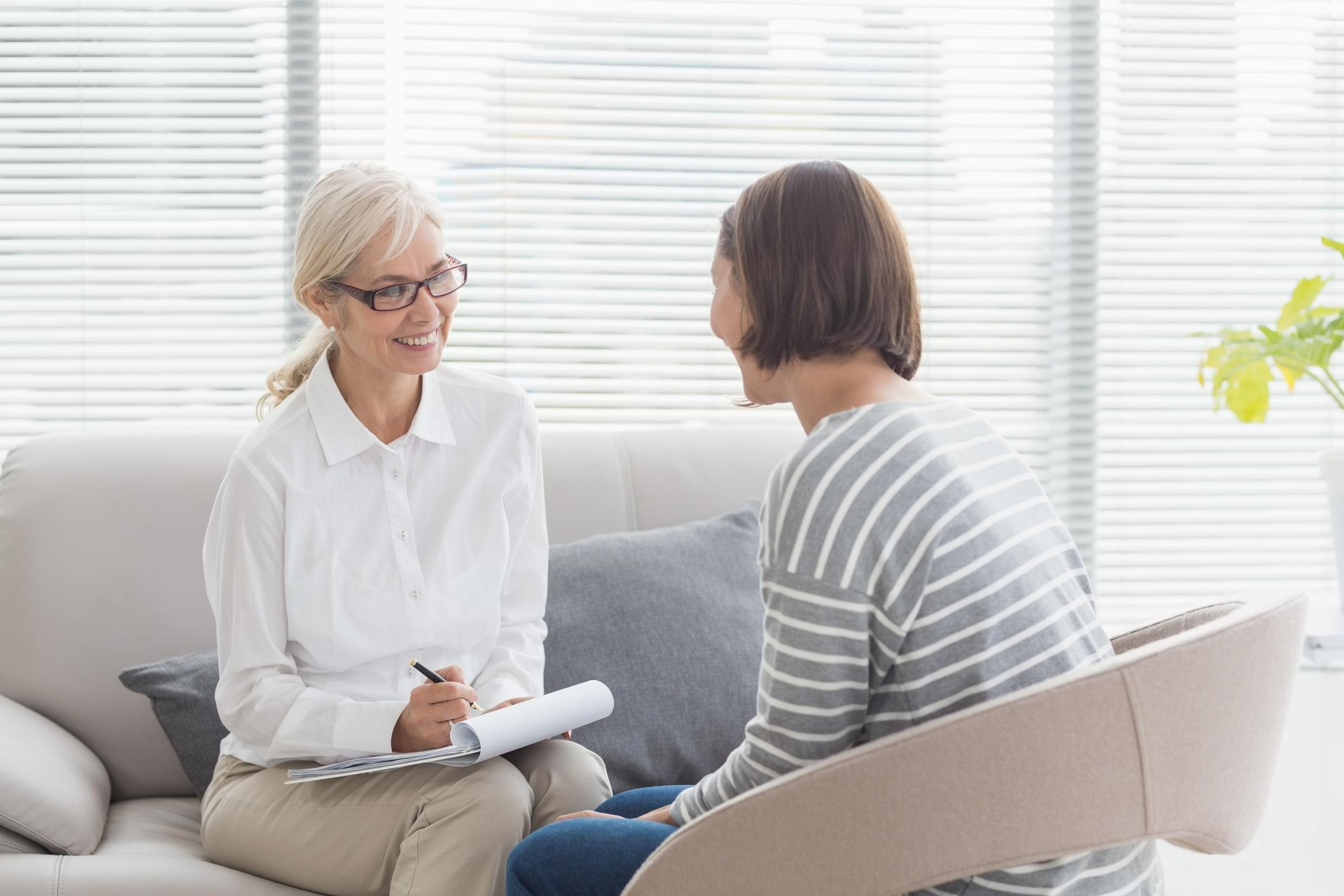 Therapist sitting with client smiling taking notes