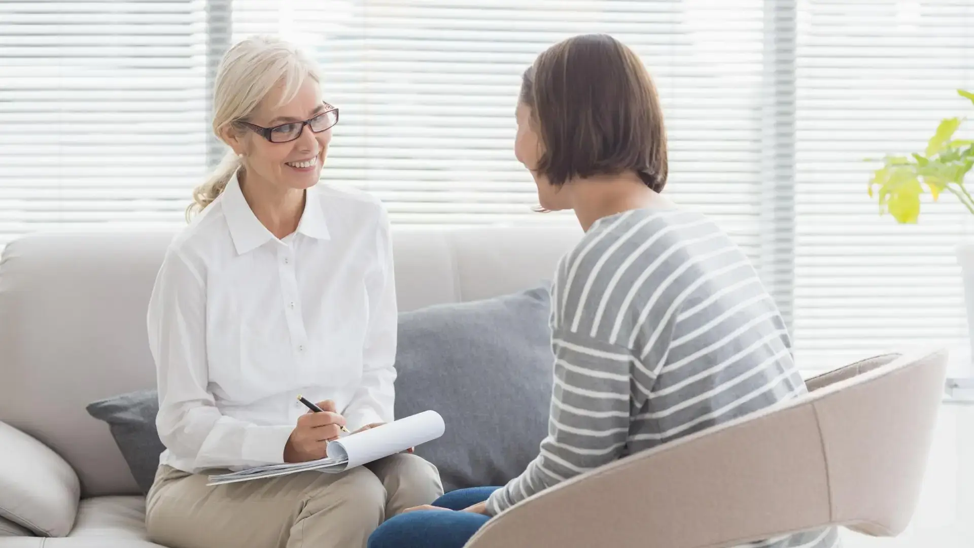 Therapist talking with client writing and smiling