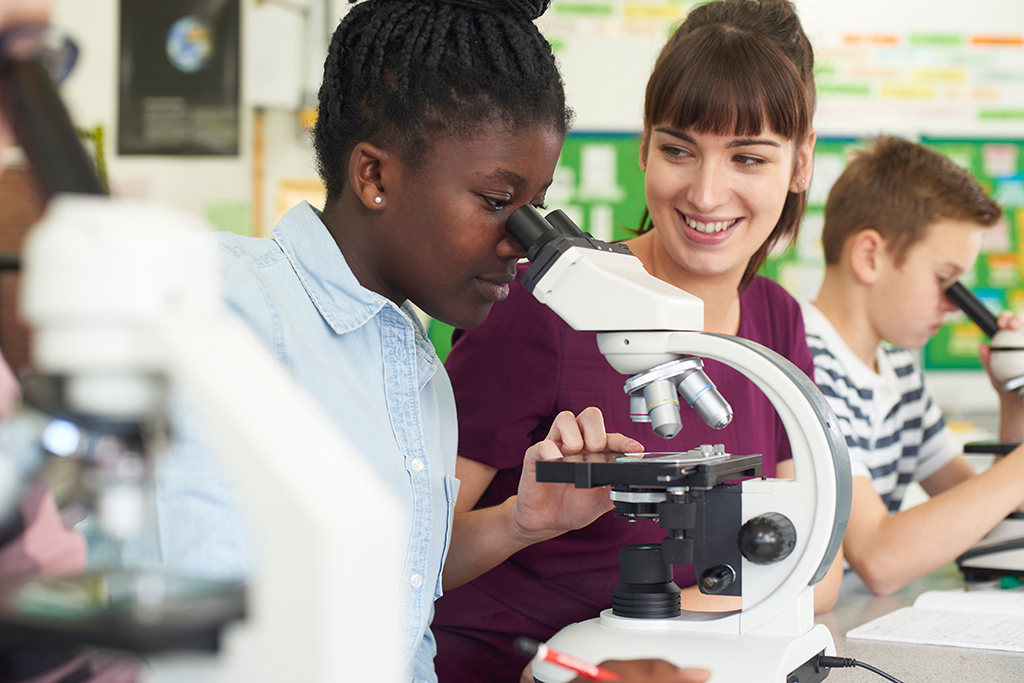 A secondary school pupil using a microsope