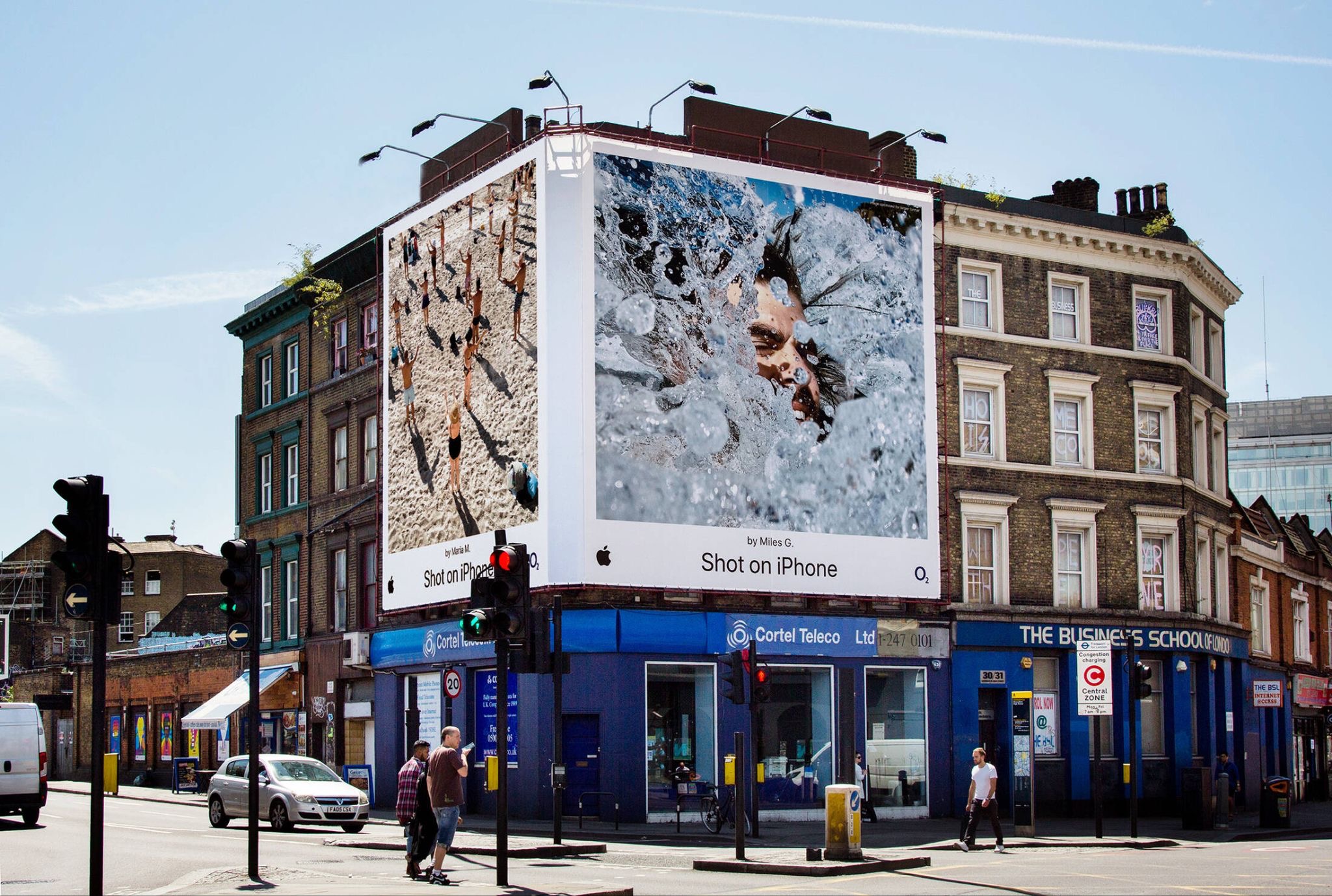 Two large "Shot on iPhone" billboards wrap around a London corner building, each crediting its photographer by name ("by Maria M." and "by Miles G.") above busy shopfronts and a traffic-light junction. [Via adsoftheworld.com]