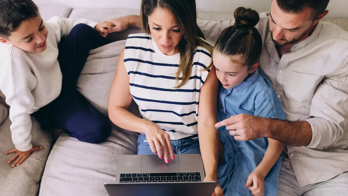 Family reviewing savings options on a laptop, representing parents exploring Trump Accounts for their children’s future.