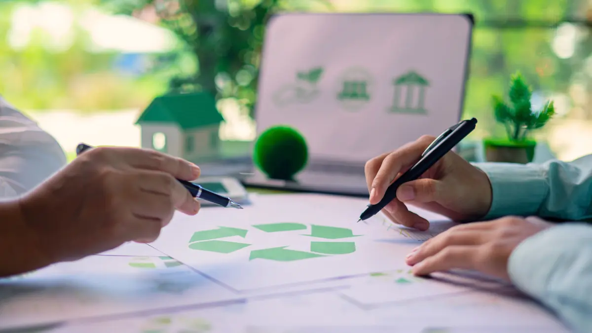 Two people reviewing sustainability plans at a desk, symbolizing eco-focused, values-driven employee benefits in the workplace.