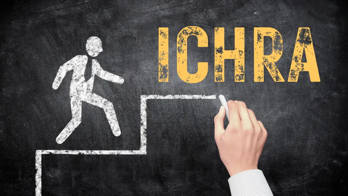 Hand drawing a chalk outline of a person climbing stairs toward the word ICHRA on a blackboard, symbolizing progress and growth with Individual Coverage Health Reimbursement Arrangements (ICHRAs).