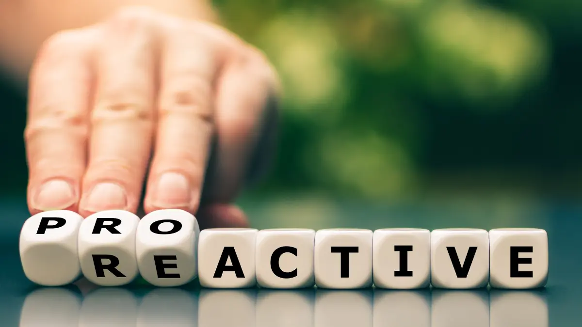 A hand flipping letter cubes from “reactive” to “proactive,” symbolizing the shift toward proactive healthcare and prevention.