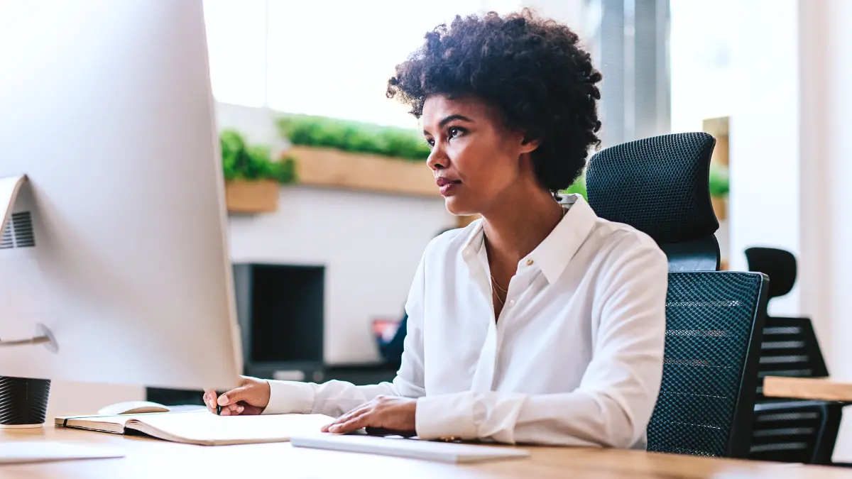 HR professional working at a desk managing employee benefits on a computer.