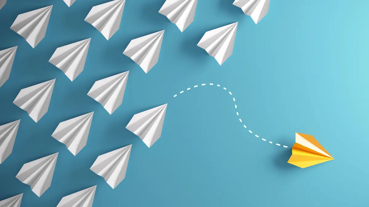 Illustration of a yellow paper airplane changing direction away from a group of white planes, symbolizing employers exploring self-funding as an alternative to traditional health insurance.