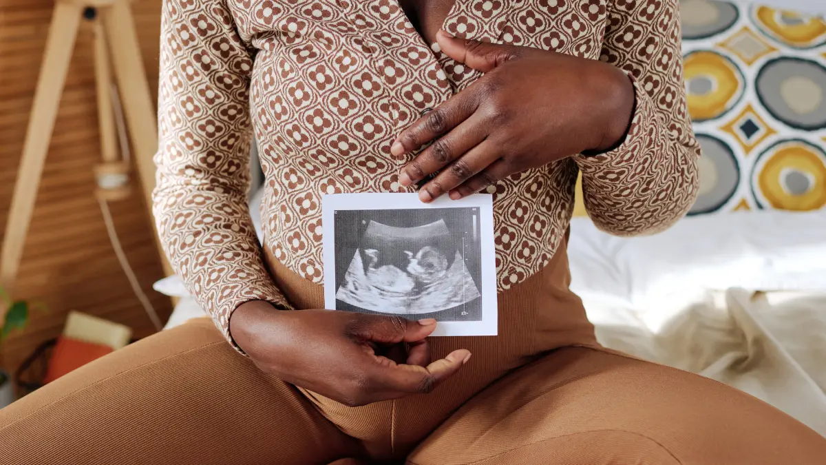 Pregnant person holding an ultrasound photo, representing fertility benefits and IVF coverage.