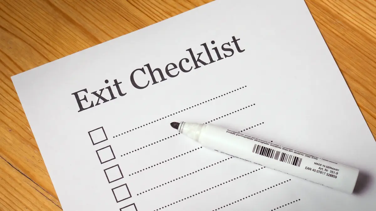 A printed exit checklist with empty checkboxes and a white marker resting on top, symbolizing the planning process for a PEO transition