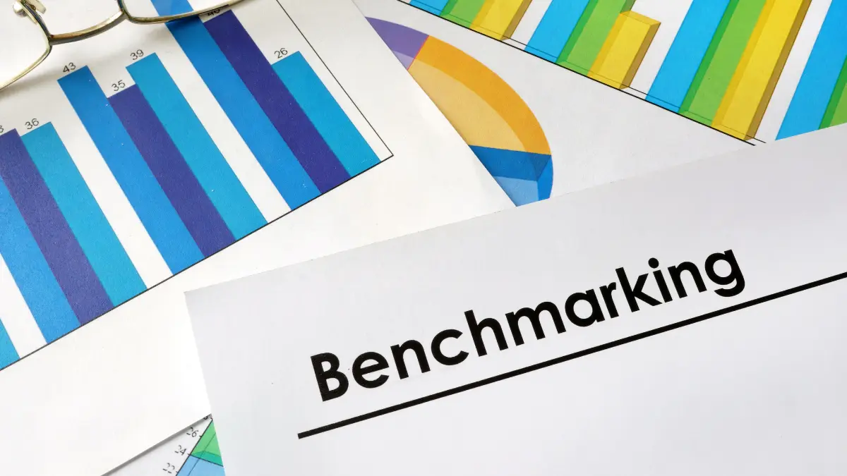 Benefits benchmarking reports and data charts spread across a desk