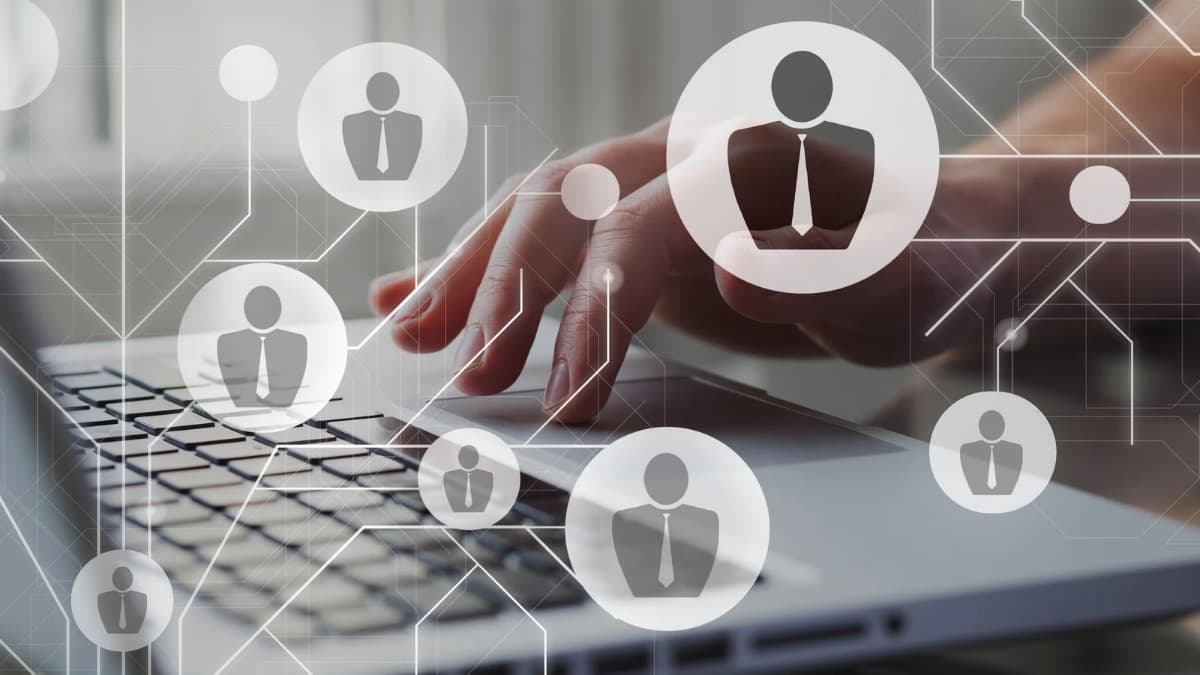 Hand using a laptop trackpad with connected employee icons overlaid, representing HR using AI for benefits questions.