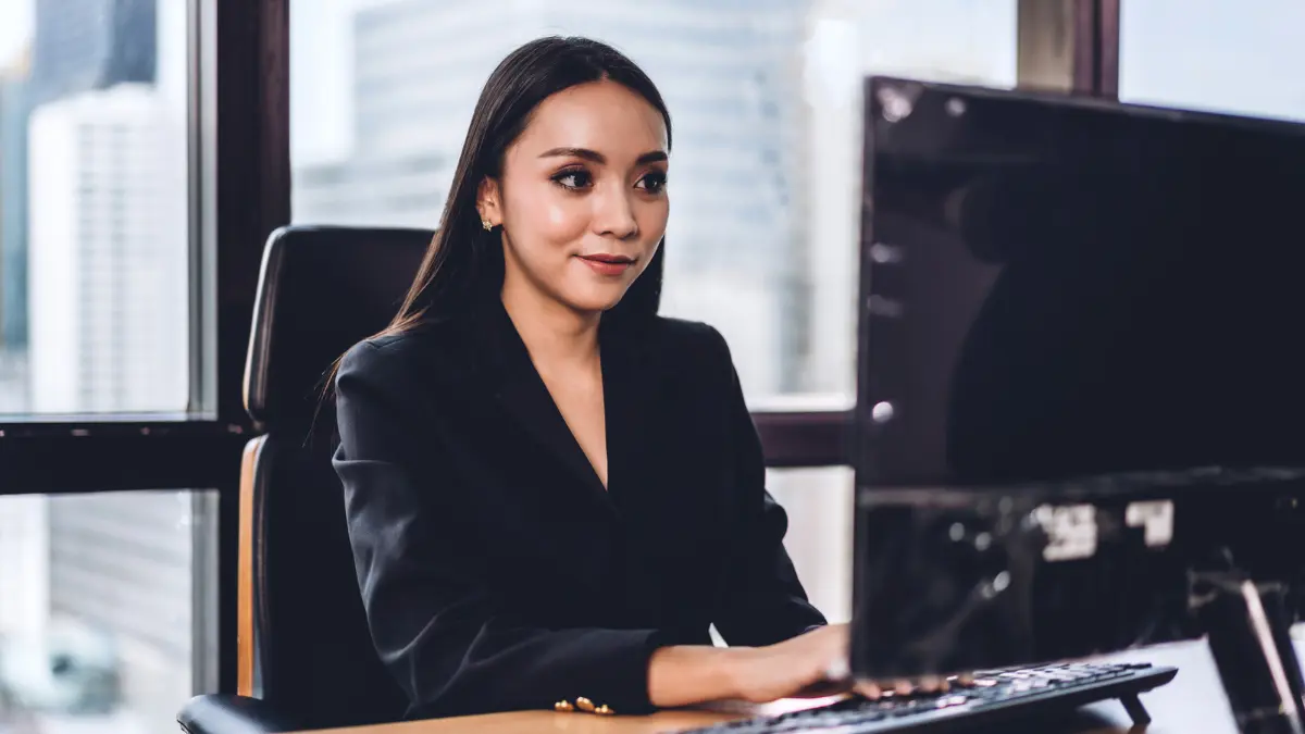 HR leader at her desk reviewing PEO employee benefits costs on a computer in a high-rise office