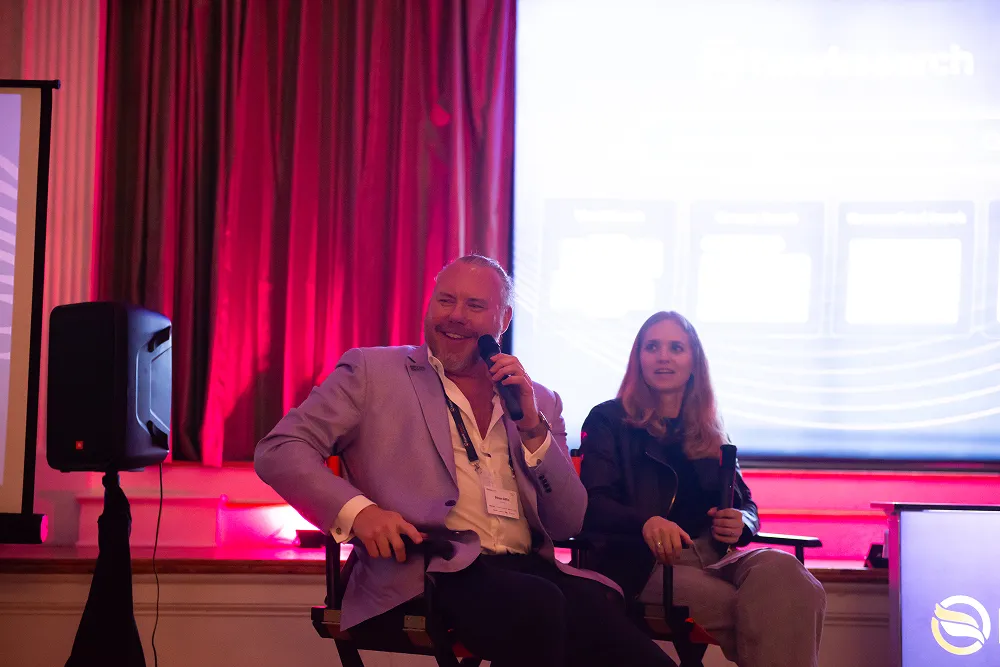 Two speakers on stage share insights and smiles during a session at the HawkSearch Customer Summit 25.