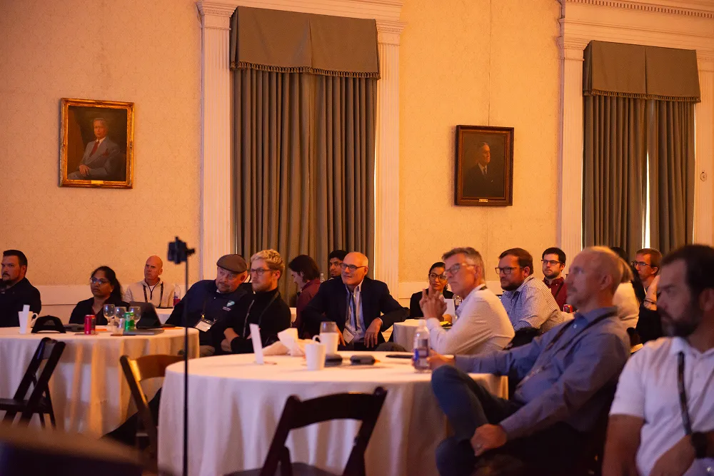 Attendees sit around tables attentively watching presentations during the HawkSearch Customer Summit 25.