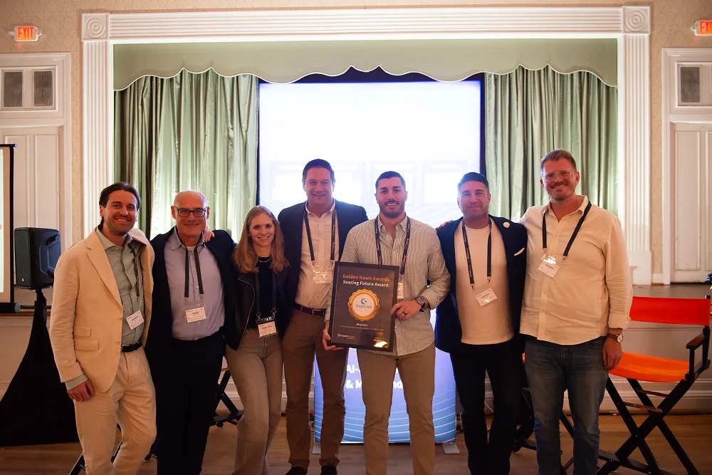 The HawkSearch team and partners pose together on stage holding an award at the Customer Summit 25.