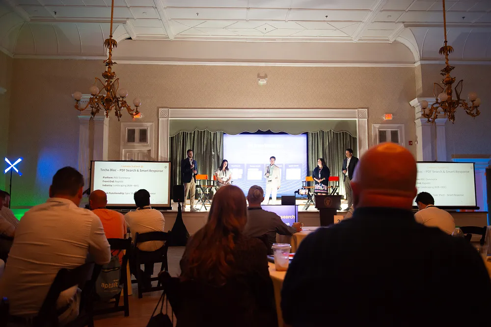 A panel of speakers presents on stage at the HawkSearch Customer Summit 25, highlighting new search and AI innovations.