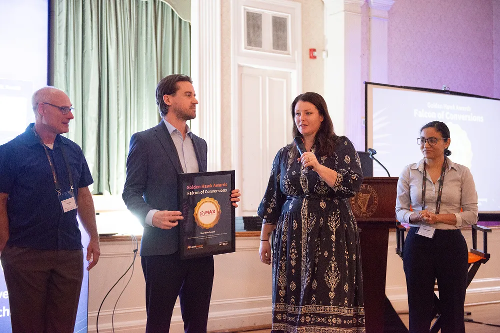 A recipient holds the “Falcon of Conversions” Golden Hawk Award plaque during the HawkSearch Customer Summit 25 presentation ceremony.