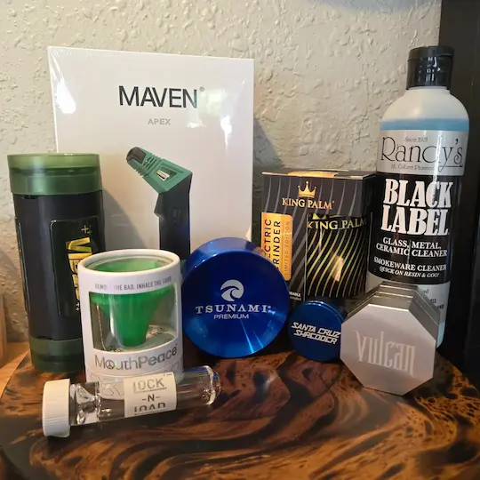 A grouping of accessories including Maven Apex, MouthPeace, Lock n Load, Tsunami Premium grinder, Santa Cruz Shredder grinder, King Palm electric grinder, Rancy's Black Label Glass, Metal, Ceramic Cleaner, and a Vulcam grinder