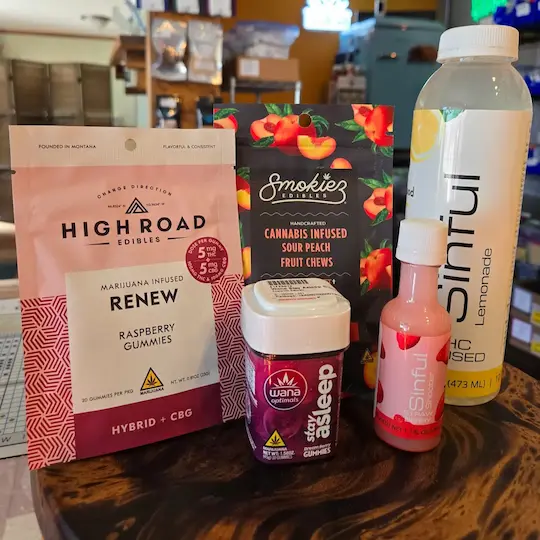 A group of cannabis-infused edibles including High Road Edibles Review Raspberry Gummies, Wana Stay Asleep Gummies, Smokiez Edibles Cannabis-Infused Sour Peach Fruit Chews, Sinful Shooter, and Sinful Lemonade
