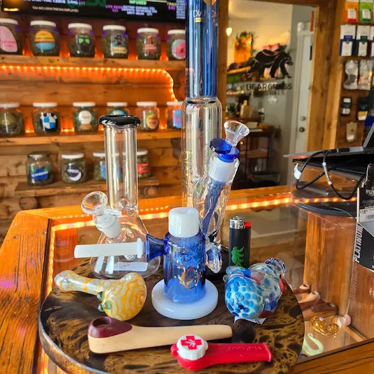 A grouping of accessories including Pulsar Glass water pipe, other water pipes, pipes, and lighters
