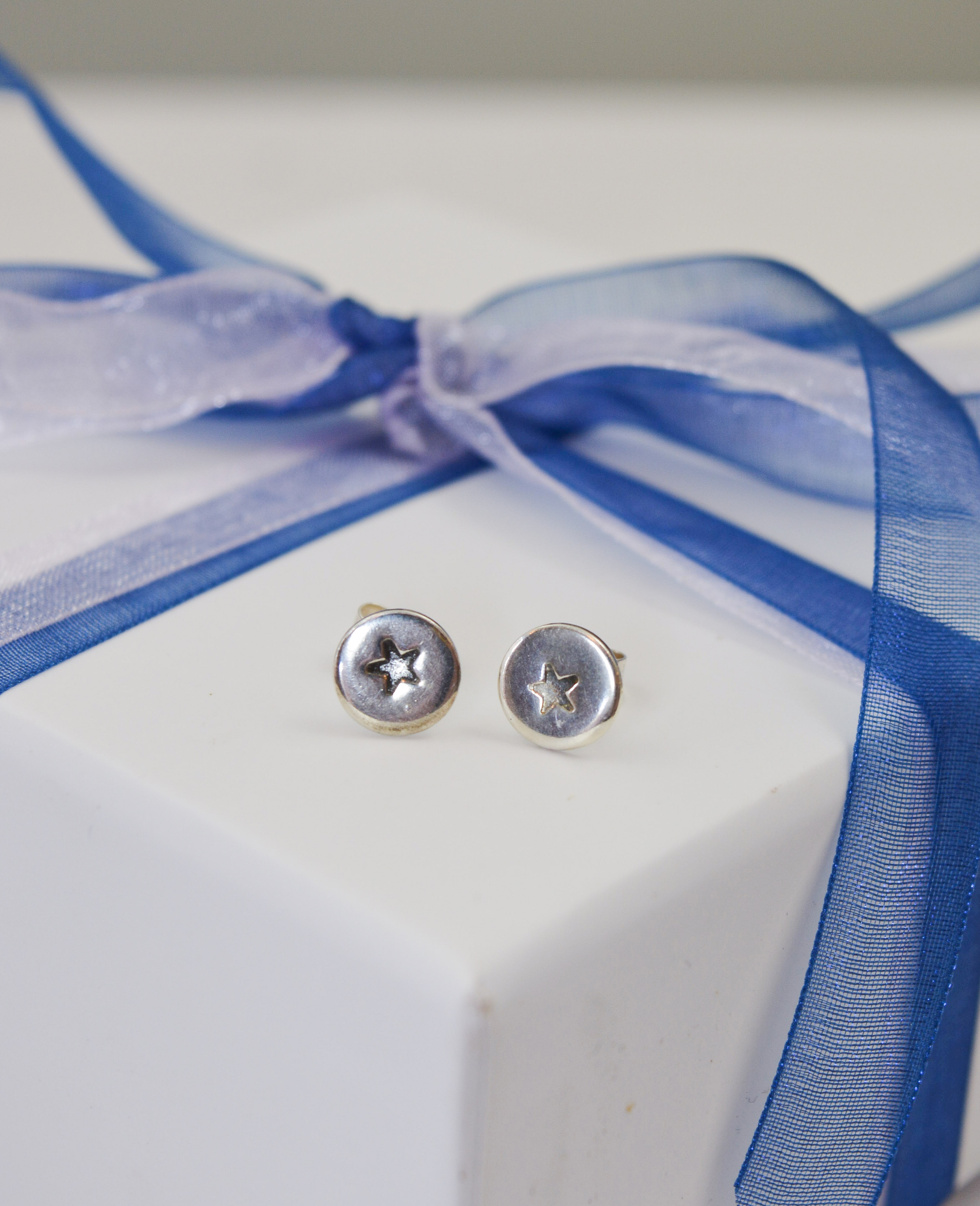 silver disk stud earringswith stamped star design on white jewellery box tied with blue ribbon