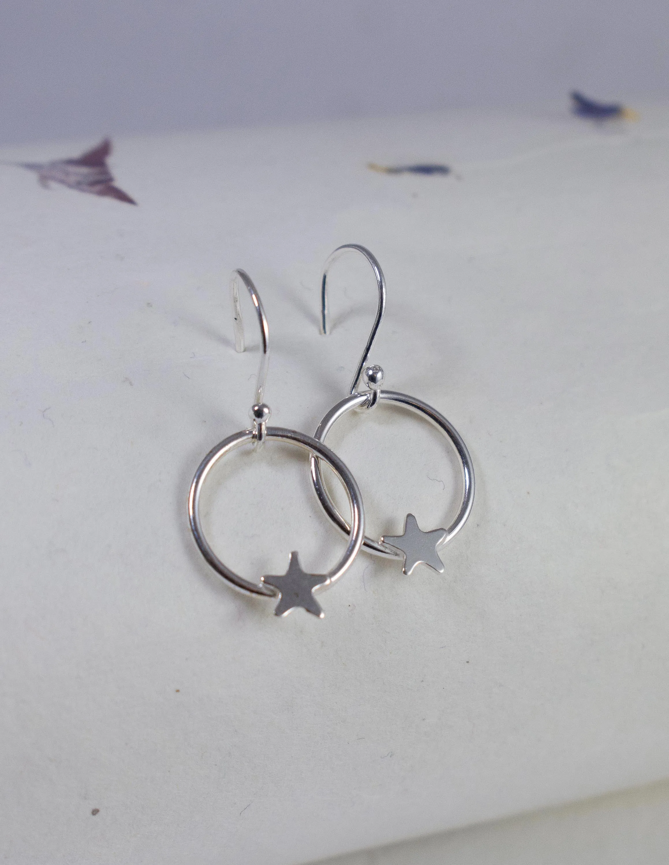 silver star hoop earrings resting on a piece of natural paper