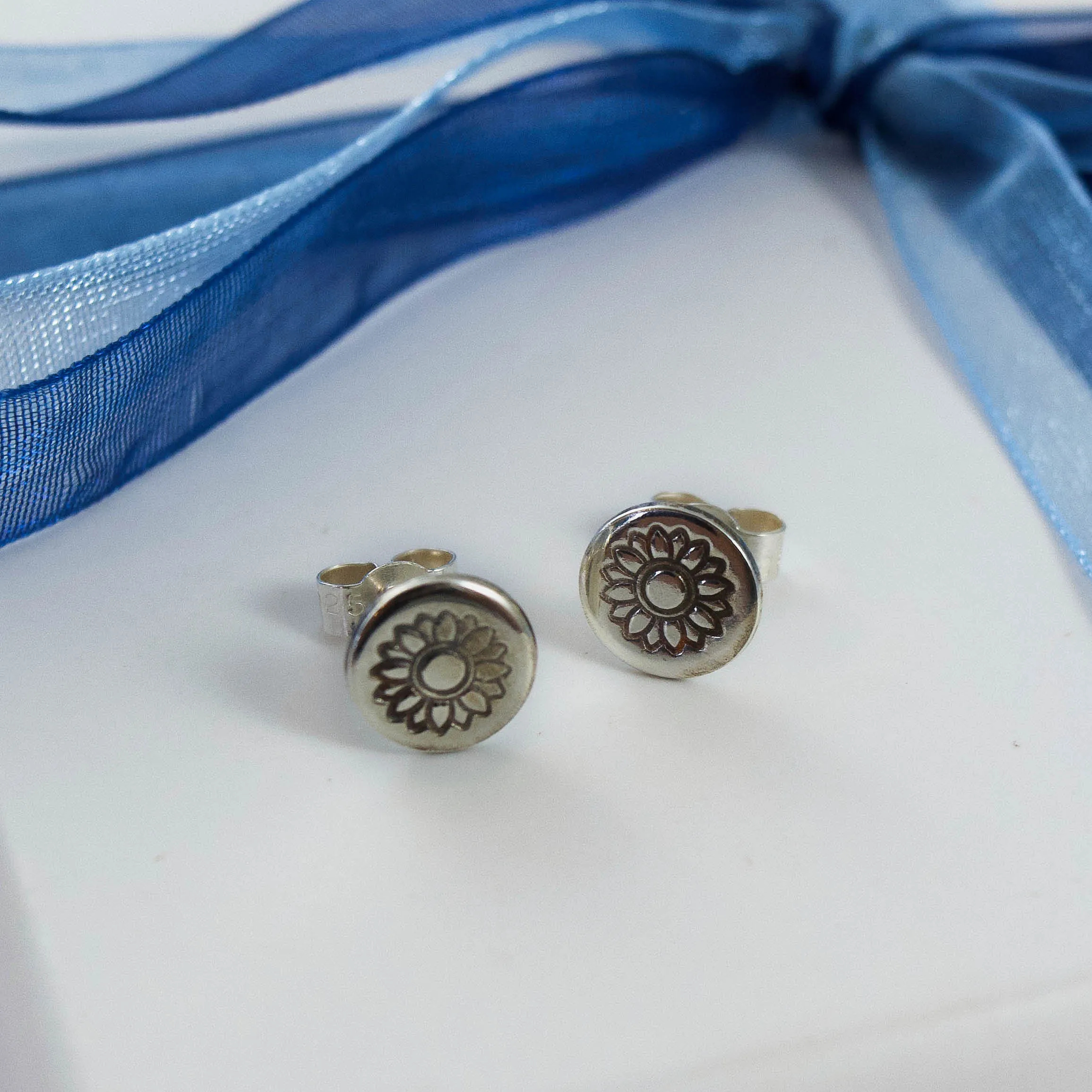 sunflower stamped earrings on white jewellery box tied with blue ribbon
