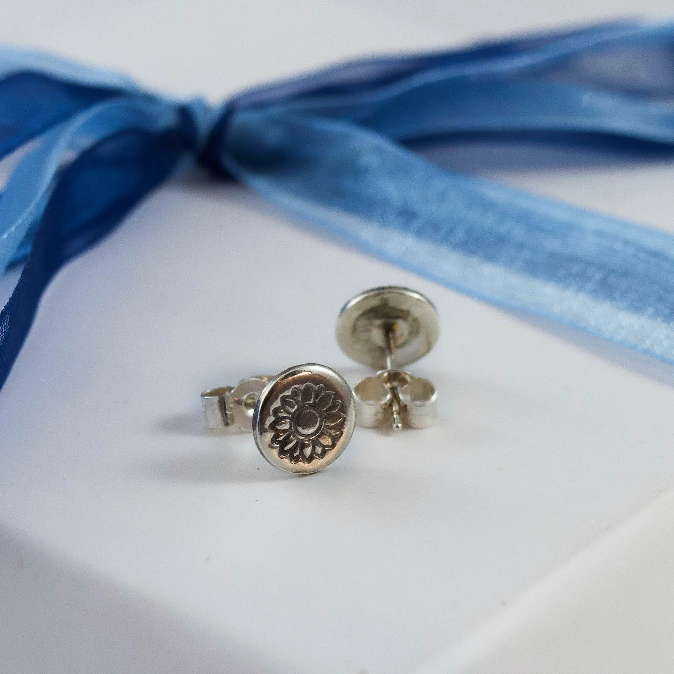 sunflower stamped earrings on white jewellery box tied with blue ribbon