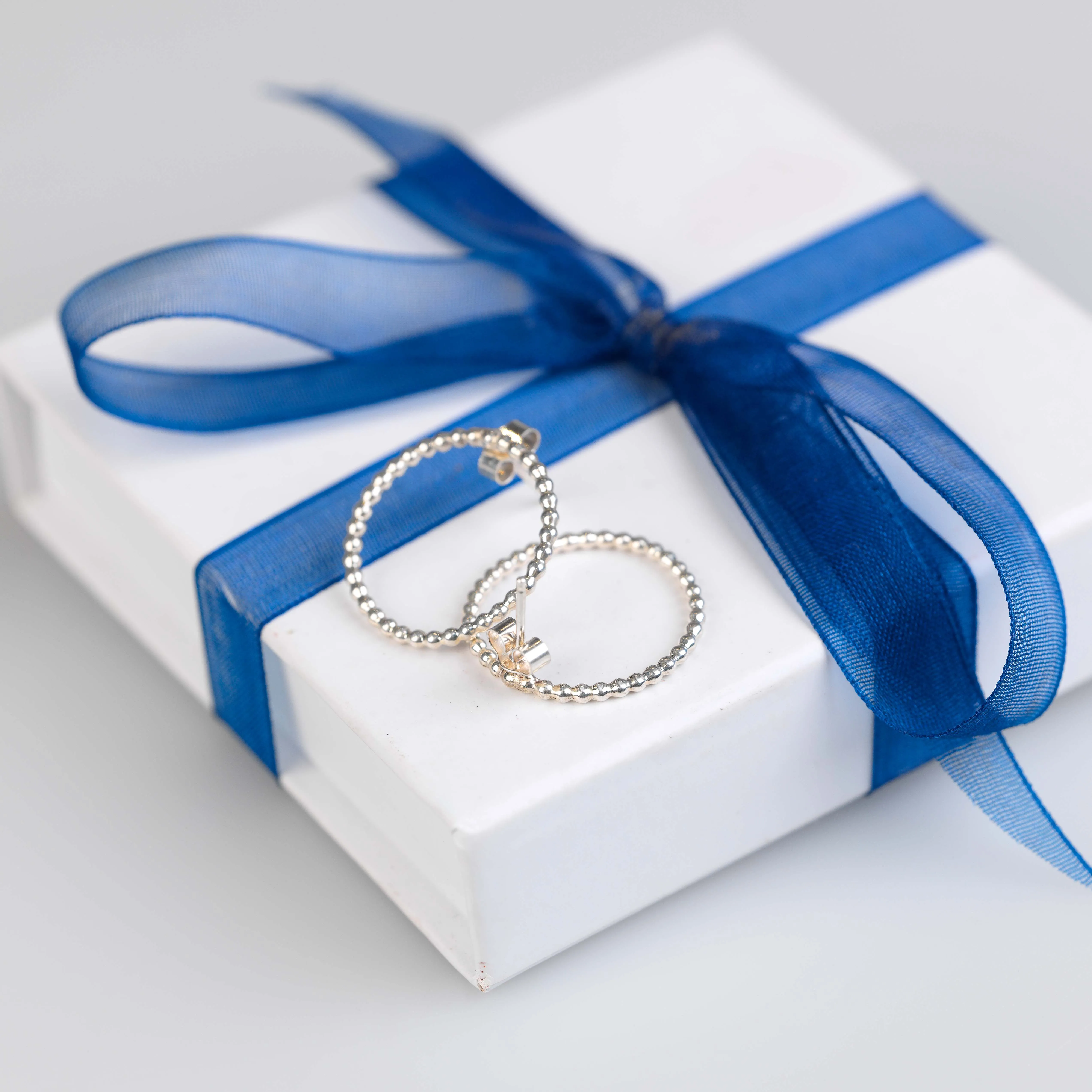 silver beaded hoop stud earrings with white jewellery box tied with blue ribbon