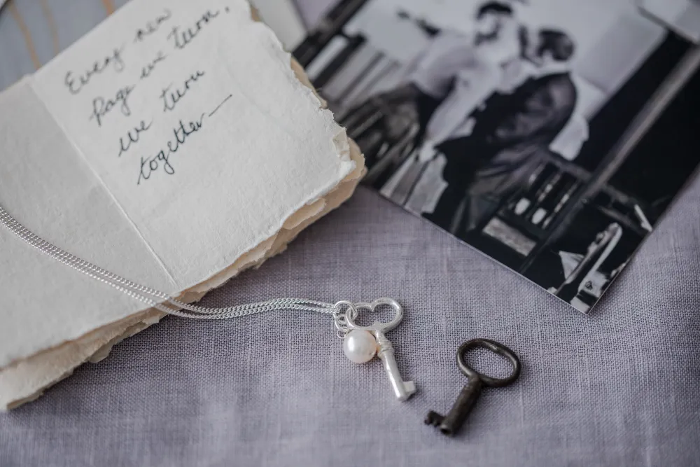 pocket key silver necklace with original key on pale blue background and with photo of people getting married and little handwritten love letter