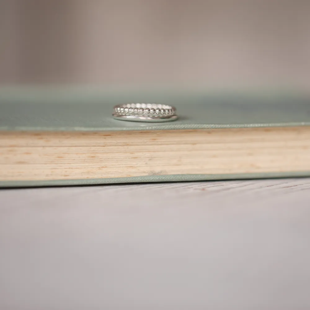 silver stacking rings one is smooth and one is beaded resting on a vintage book