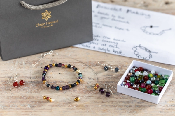Jewellery making kit including instructions and christmas bead kit, photo also shows gift bag and finished examples on a wooden table